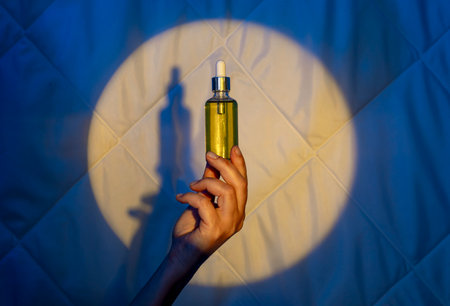 woman hand on the background of a quilt in the light of the moon with dropper with sleeping oil. Fighting insomniaの写真素材