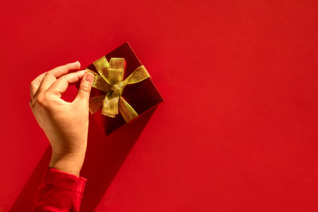 Unwrapping Joy: Womans Hand Reveals the Magic Inside the Golden-Glazed Gift. Christmas backgroundの写真素材