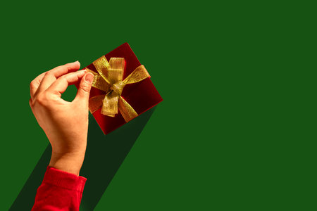 Unwrapping Joy: Womans Hand Reveals the Magic Inside the Golden-Glazed Gift. Christmas backgroundの写真素材