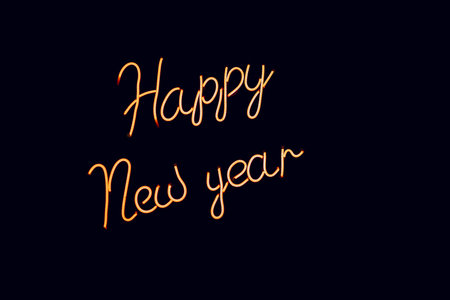 Glowing blurry orange inscription New Year on a black background. Vintage image in dark colorsの写真素材