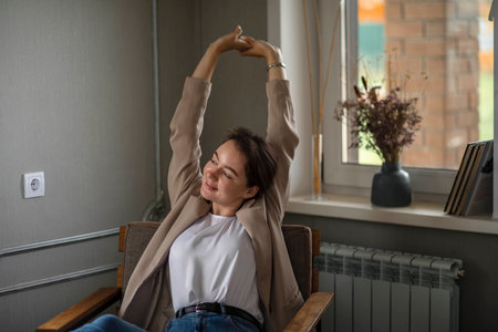 Smiling Young caucasian Female Manager Sitting On Chair Stretching Her Arms. Work-life-balanceの写真素材