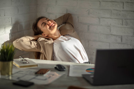 Smiling Young caucasian Female Manager Sitting at the table Stretching Her Arms. Work-life-balanceの写真素材