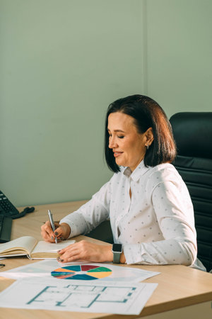 Young Happy Businesswoman Using diagram in Modern Office. Stylish Beautiful Manager Smiling, Working on Financial and Marketing Projects.の写真素材
