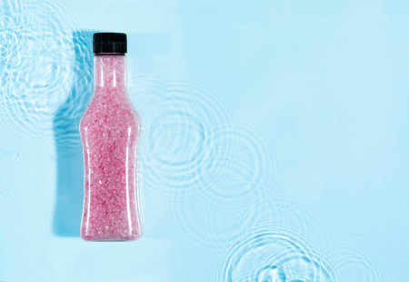 jar with spa salt on blue water background with splashes. Mockup of cosmetic packagingの写真素材