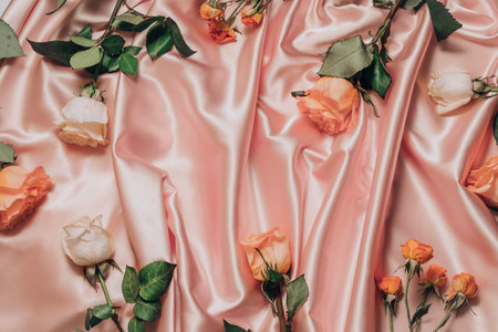 Simple beautiful roses flowers on satin fabric background. Gentle pink pearl cream waves folder satin fabric, with hammers of light, the surface, flat lay back up copy space for product or textの写真素材