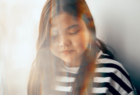 The blurred face of a girl with closed eyes and a serene expression, dressed in stripes, gives free rein to her imagination, embodying the bizarre nature of youthful daydreams.の写真素材
