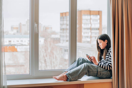 Urban Solitude : A serene moment of a young girl immersed in her thoughts by the window, the urban sprawl stretched out before herの写真素材