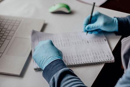 professional working with numerical data. Clad in blue gloves, person carefully logs information,...