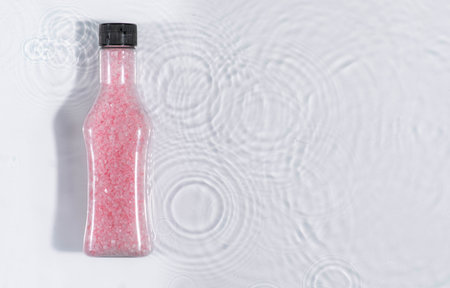 jar with spa salt on blue water background with splashes. Mockup of cosmetic packagingの写真素材