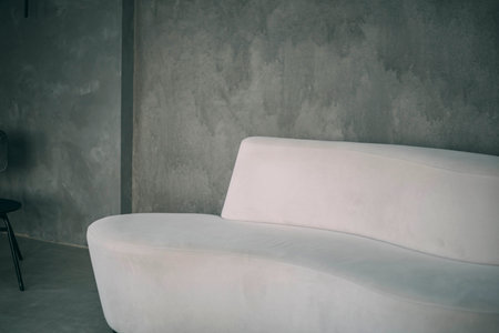 essence of modern tranquility with a stylish sofa set against a calm, grey concrete wall, evoking a sense of peace and refined interior designの写真素材