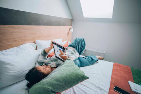 In quiet comfort of her bedroom, a girl uses her tablet to sketch, finding solace and therapeutic...