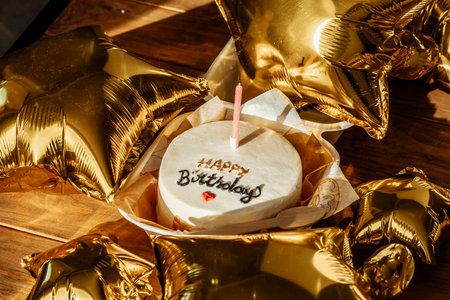 gold balloons and a beautifully simple birthday cake to mark the passage into adulthoodの写真素材
