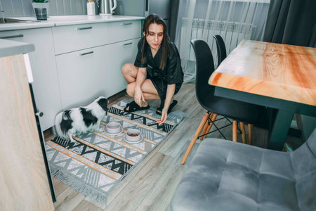 woman caring for dog in modern kitchen, concept of pet care and contemporary lifestyleの写真素材