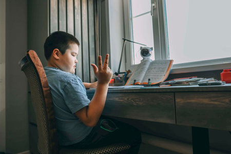 asian boy in blue shirt sitting at desk counting on fingers during homework, homeschooling, kids...