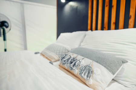 Cozy glamping tent interior with a neatly made bed. Soft pillows and a wooden headboard create a...