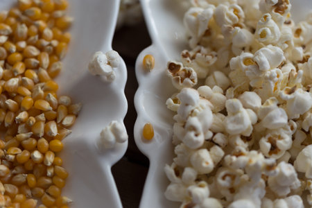 popcorn and popcorn grains on white plate on wooden background