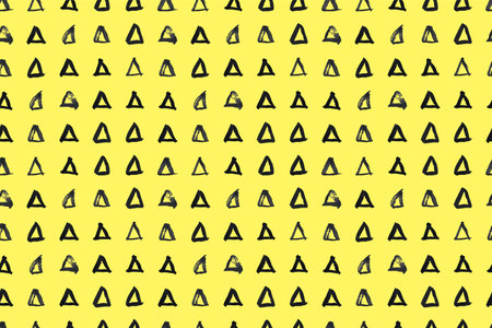 Dash pattern on yellow background. Wrapping paper with small black triangles painted with a brush. Seamless simple minimal ornament. Abstract geometric grunge vector texture painted by ink.のイラスト素材