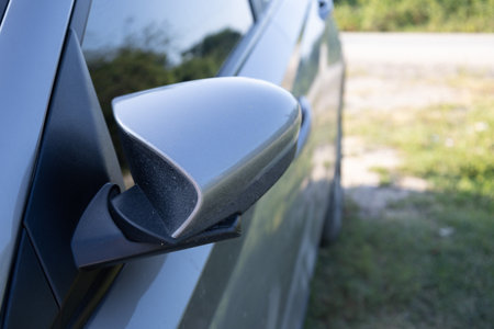 Close up view of side mirror on a gray car parked outdoors in natural sunlightの写真素材