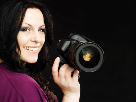 smiling brunette photographer woman holding camera over dark background