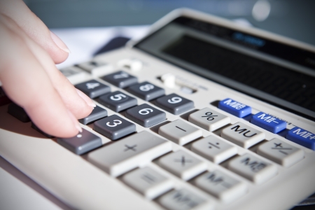 human's hand touching calculator in officeの写真素材