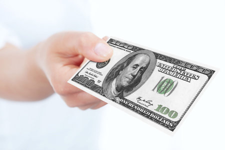 one hundred dollars banknote holded by hand over white background
