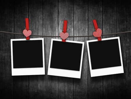 photos hanging on clothesline with heart clothespin over wooden backgroundの写真素材