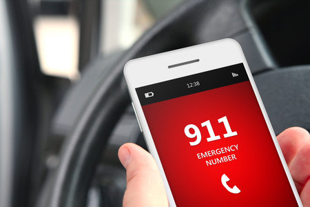 hand holding cellphone with emergency number 911 in car