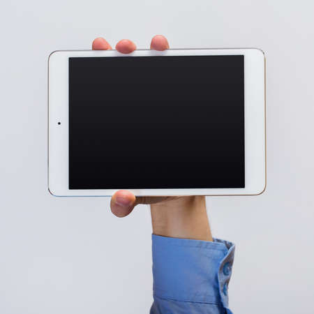 White tablet pc in hands over gray backgroundの写真素材