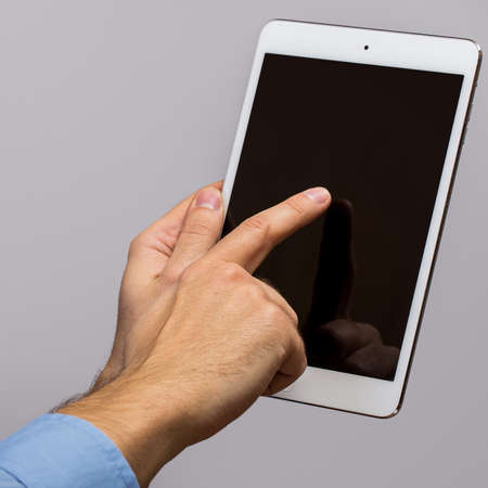 White tablet pc in hands over gray backgroundの写真素材