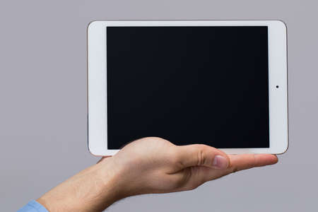 White tablet pc in hands over gray backgroundの写真素材