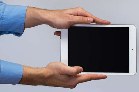 White tablet pc in hands over gray backgroundの写真素材