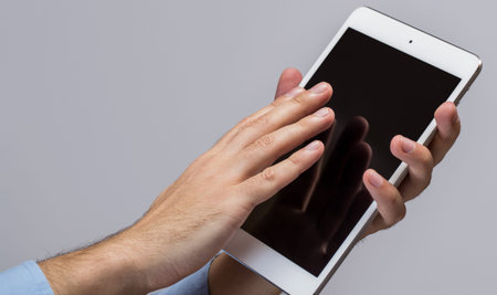 White tablet pc in hands over gray background