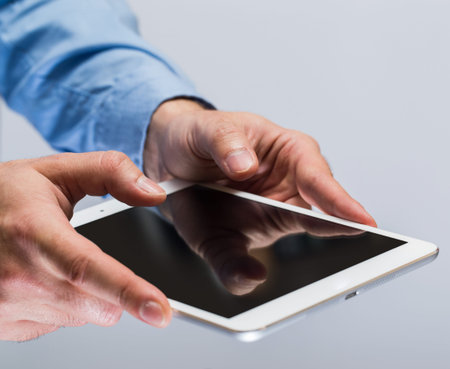 White tablet pc in hands over gray background