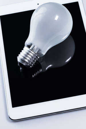 Close up of light bulb and white tablet pcの写真素材