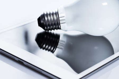 Close up of light bulb and white tablet pcの写真素材