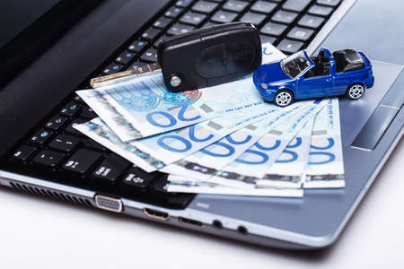 Toy car and banknotes over laptop keyboardの写真素材