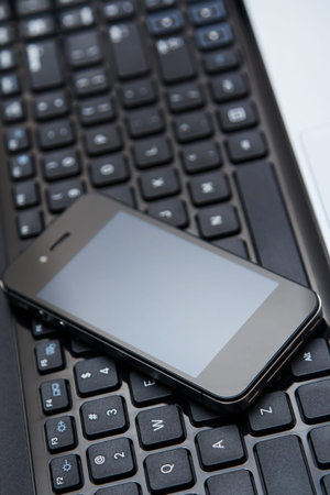 Smartphone lying above laptop keyboard