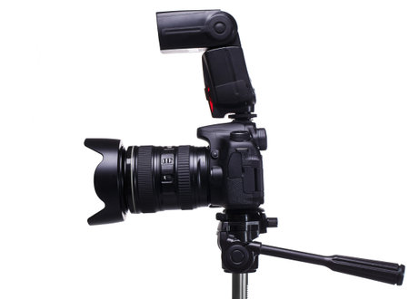 DSLR camera on tripod with external flash over white background