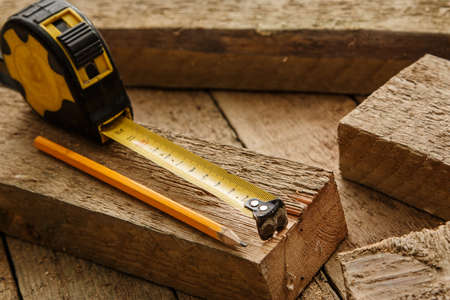 Measure tape and pencil on wooden palnksの写真素材