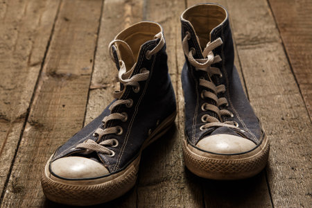 Dirty gumshoes on wooden background