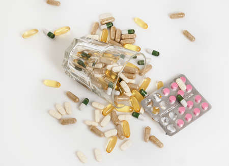 Glass and pile of different colorful pillsの写真素材