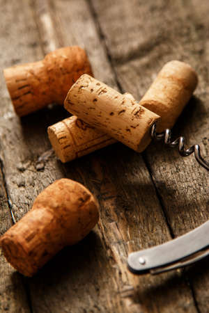 Corkscrew and wine corks on wooden surfaceの写真素材