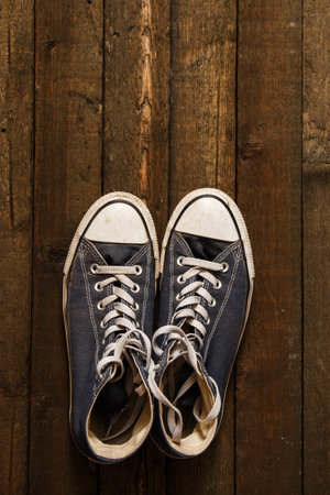 Dirty gumshoes on wooden background