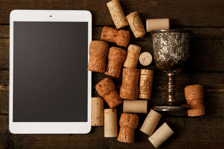 Tablet pc and wine corks over wooden surfaceの写真素材