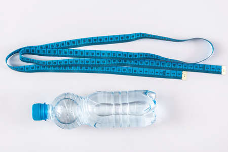 Bottle with water and measure tape on white backgroundの写真素材