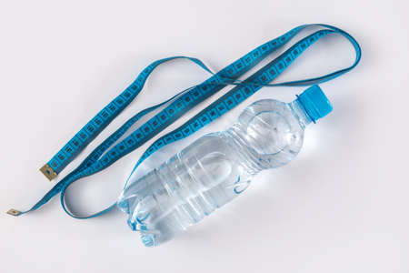 Bottle with water and measure tape on white backgroundの写真素材