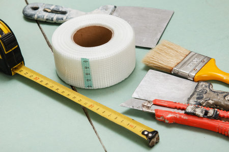 Reinforcing net and instruments over plasterboard surface