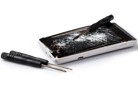 Smartphone with cracked display and screwdrivers