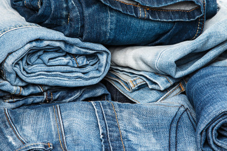 Stack of different blue jeans on white background