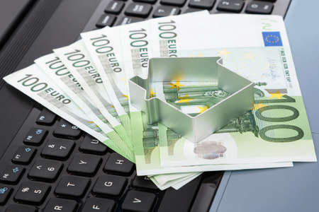 House and euro banknotes over laptop keyboardの写真素材
